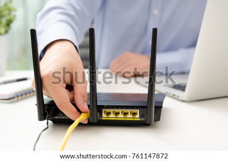 Man plugs Ethernet cable into router. router wireless wire broadband home office cable plug concept