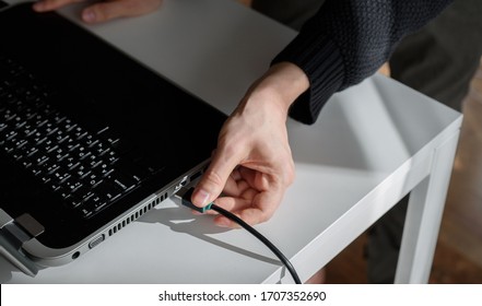 a man plugs a HDMI cable into a laptop with his hand - Shutterstock ID 1707352690