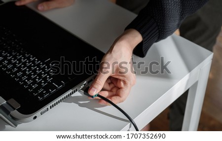 a man plugs a HDMI cable into a laptop with his hand
