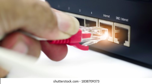  Man Plugs Internet Cable Into The Router.LAN Network And Internet Connection, Ethernet RJ45 Cable Plug To Lan Port,modem Router.                              