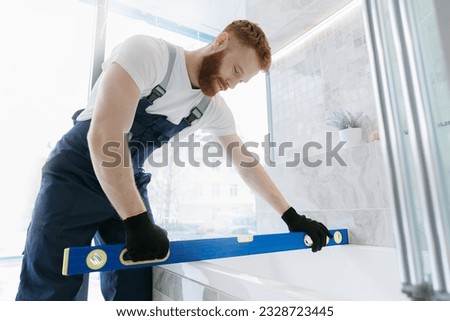 Man plumber installing white bath and control install. Repair service plumbing in bathroom.