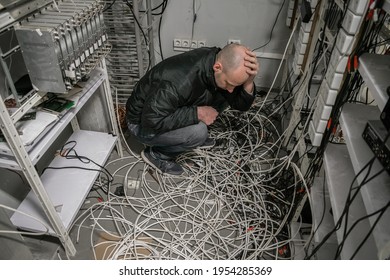 The Man Is In A Plundered Server Room. A Sad Technician Sits Near A Pile Of Wires And Holds His Head With His Hands In An Empty Datacenter.