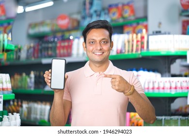 Man pointing at blank mobile phone screen in supermarket