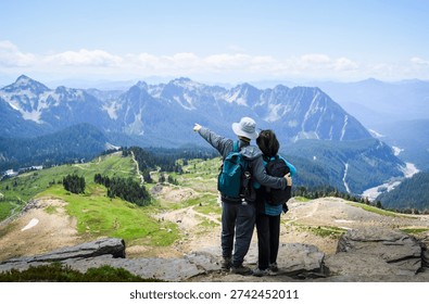 Man pointing to the distant view. Couple enjoying the view from Skyline Loop Trail. Mt Rainier National Park. Washington State. 