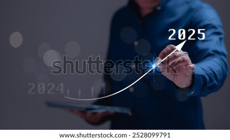 A man is pointing a graph on a tablet with a blue shirt. The graph shows a line that is rising to the right, with the number 2025 at the top. Concept of progress and growth