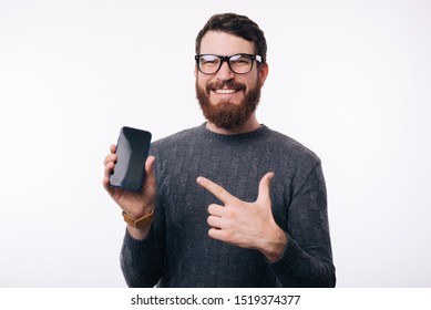 Man Pointing At His Blank Screen Phone. He Is Wearing Glasses And A Gray Sweater.