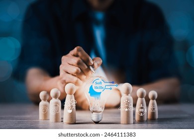A man is pointing at a light bulb on a table with wooden figurines. Concept of Soft Skills, creativity and innovation - Powered by Shutterstock