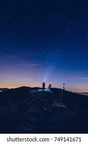 Man pointing light from his flashlight to the sky. Night camp in mountains. Starry night