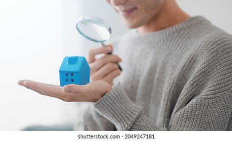 
A Man Pointing A Magnifying Glass At A Model Of A House