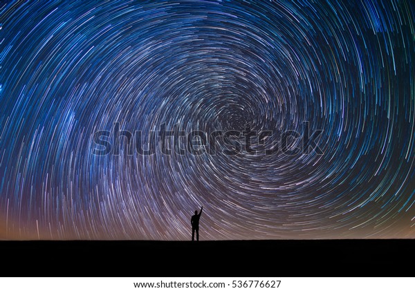 Man Pointing North\
in a spiral star trail