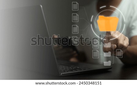 A man is pointing at a yellow folder on a laptop. The folder is labeled 