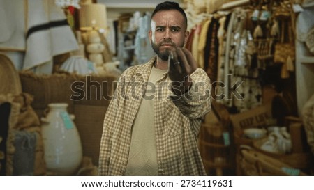 Man points finger forward inside a retail building, hand extended and stern expression; anger confrontation.
