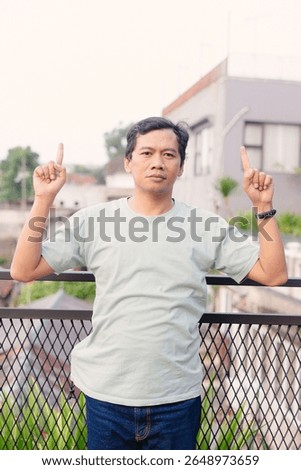 A man points upwards with both hands, set against the backdrop of an urban scene with a neutral color palette indicating a thoughtful or perhaps instructive moment.