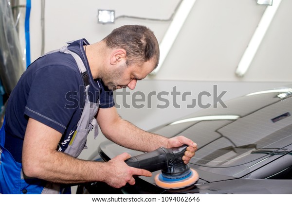 A man polishes a
black car with a polisher