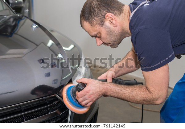 A man polishes a\
black car with a polisher