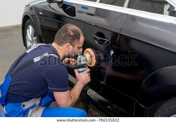 A man polishes a
black car with a polisher