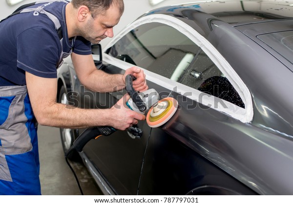 A man polishes a\
black car with a polisher