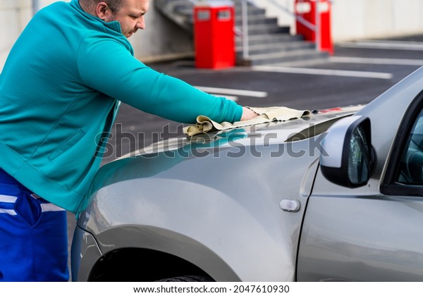 Man polishes car, using\
microfiber cloth. Man washing and wiping car in Romania, Bucharest,\
2021