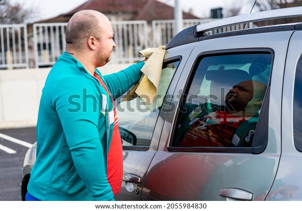 Man polishes car, using\
microfiber cloth. Man washing and wiping car in Romania, Bucharest,\
2021