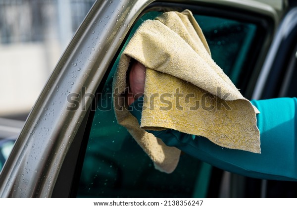 Man polishes car, using microfiber cloth. Man washing\
and wiping car
