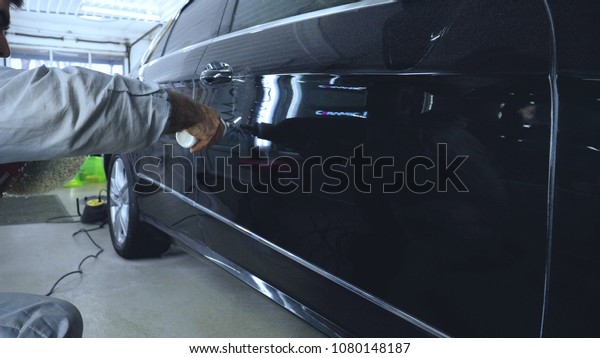 The man polishes the cars from body\
scratches, car service, autoshop, washing,\
polishing.