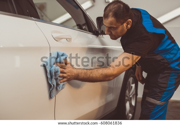 A\
man polishes a white machine with a polishing\
machine