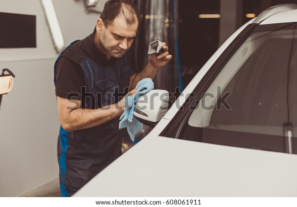 A\
man polishes a white machine with a polishing\
machine