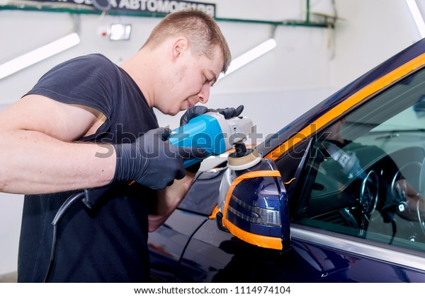 A man is polishing a blue car. Polishing\
machine and polishing paste for\
gloss.