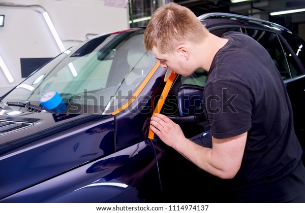 A man is polishing a blue car. Polishing\
machine and polishing paste for\
gloss.
