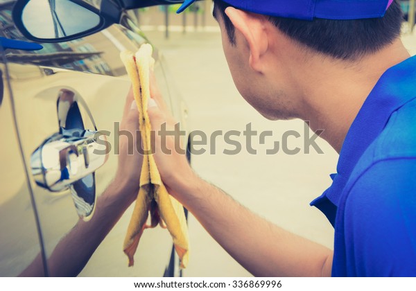 A man polishing car\
with microfiber cloth, car detailing (or valeting) concept, vintage\
tone image
