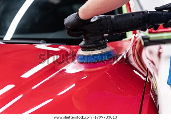 Man\
polishing car varnish with hand electric\
polisher.