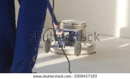 Man polishing marble floor in modern office building. Man works with grinding machine for floor