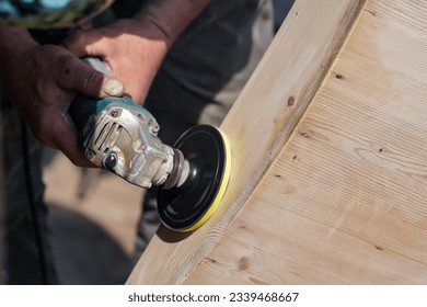 Man polishing wooden chest with old angle grinder during sunny day, closeup detail to hands without gloves - Powered by Shutterstock