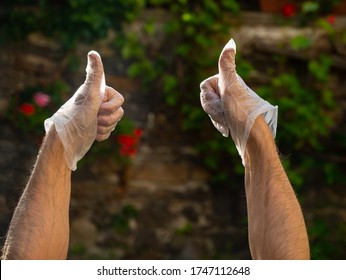 Man In Polyethylene Gloves Outdoors. Male Showing OK Sign