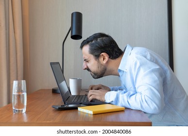 Man With A Poor Eyesight Working In His Laptop, Struggling To See