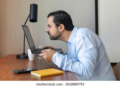 Man With A Poor Eyesight Working Inhis Laptop, Struggling To See