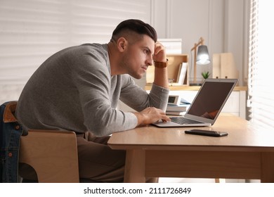 Man with poor posture using laptop at table indoors - Shutterstock ID 2111726849