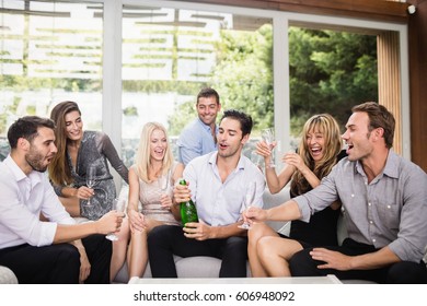 Man Popping Champagne Bottle While Celebrating With Friends