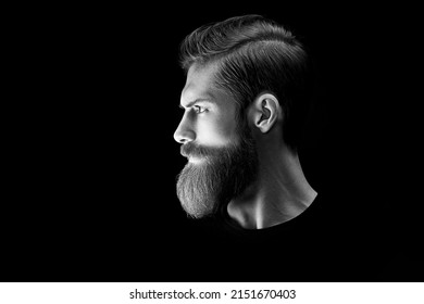 Man portrait. Black and white dramatic light portrait of confident young bearded man looks into the distance. Stylish young man red beard. Light accent on the beard and hair
