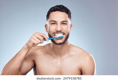 Man, portrait and happy with brushing teeth in studio for oral hygiene, mouth cleaning and morning routine. Mockup, person and toothbrush for fresh breath, dental and healthy gums on gray background - Powered by Shutterstock