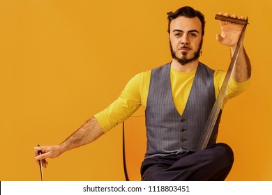 Man Portrait Sitting On Chair And Holding Musical Saw