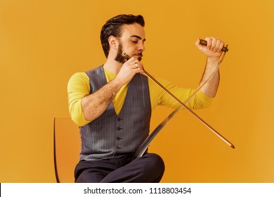 Man Portrait Sitting On Chair And Playing Musical Saw