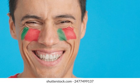 Man with a portuguese flag painted on the face smiling - Powered by Shutterstock