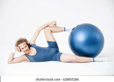 Man posing lying on floor, holding exercise ball with legs