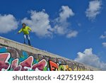 A man posing on a wall with a longboard