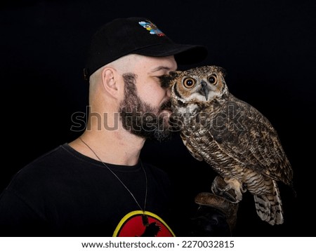 Man posing in photoshoot with owl on black isolated background