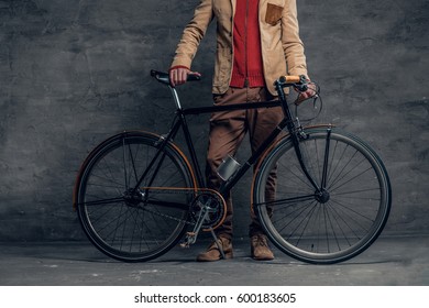 A Man Posing With Single Speed Bicycle Over Grey Background.