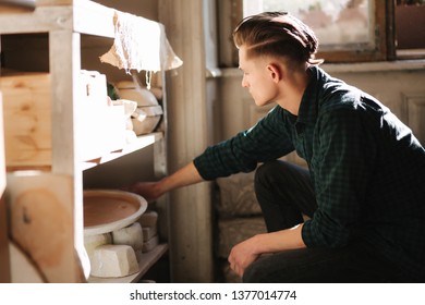 Man potter looking for ware for a work. Young man potter in his workshop. Handsome man work