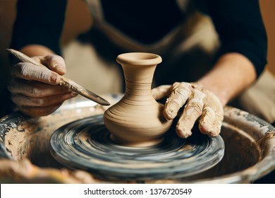 Man potter working on potters wheel making ceramic pot from clay in pottery workshop. art concept