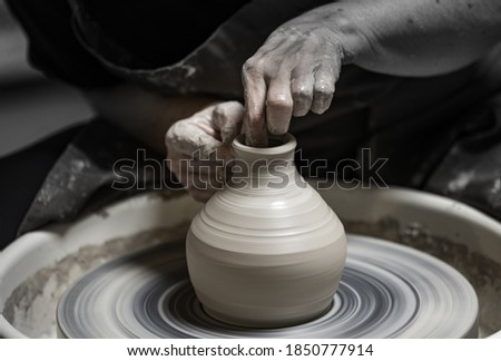 Man potter working on potters wheel making ceramic pot from clay 